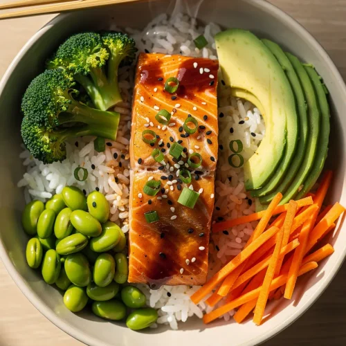 Teriyaki salmon bowl recipe with rice, avocado, broccoli, carrots, and edamame topped with sesame seeds and green onions.