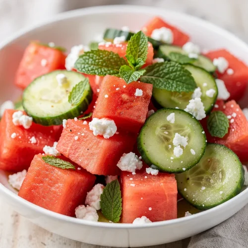 Watermelon cucumber salad with feta and fresh mint in a white bowl